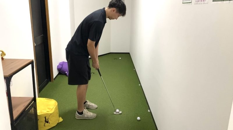 室内のパターグリーンで練習をする男性