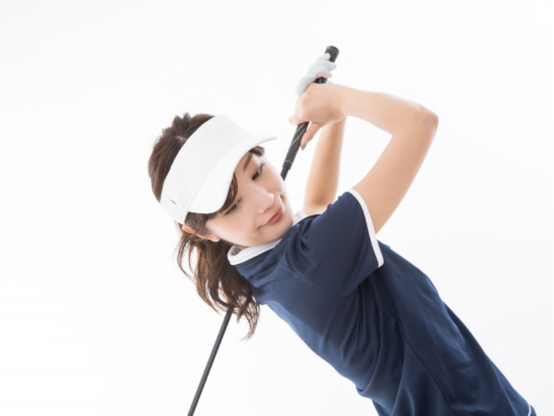 ナイスショットを決めて微笑む女性ゴルファー